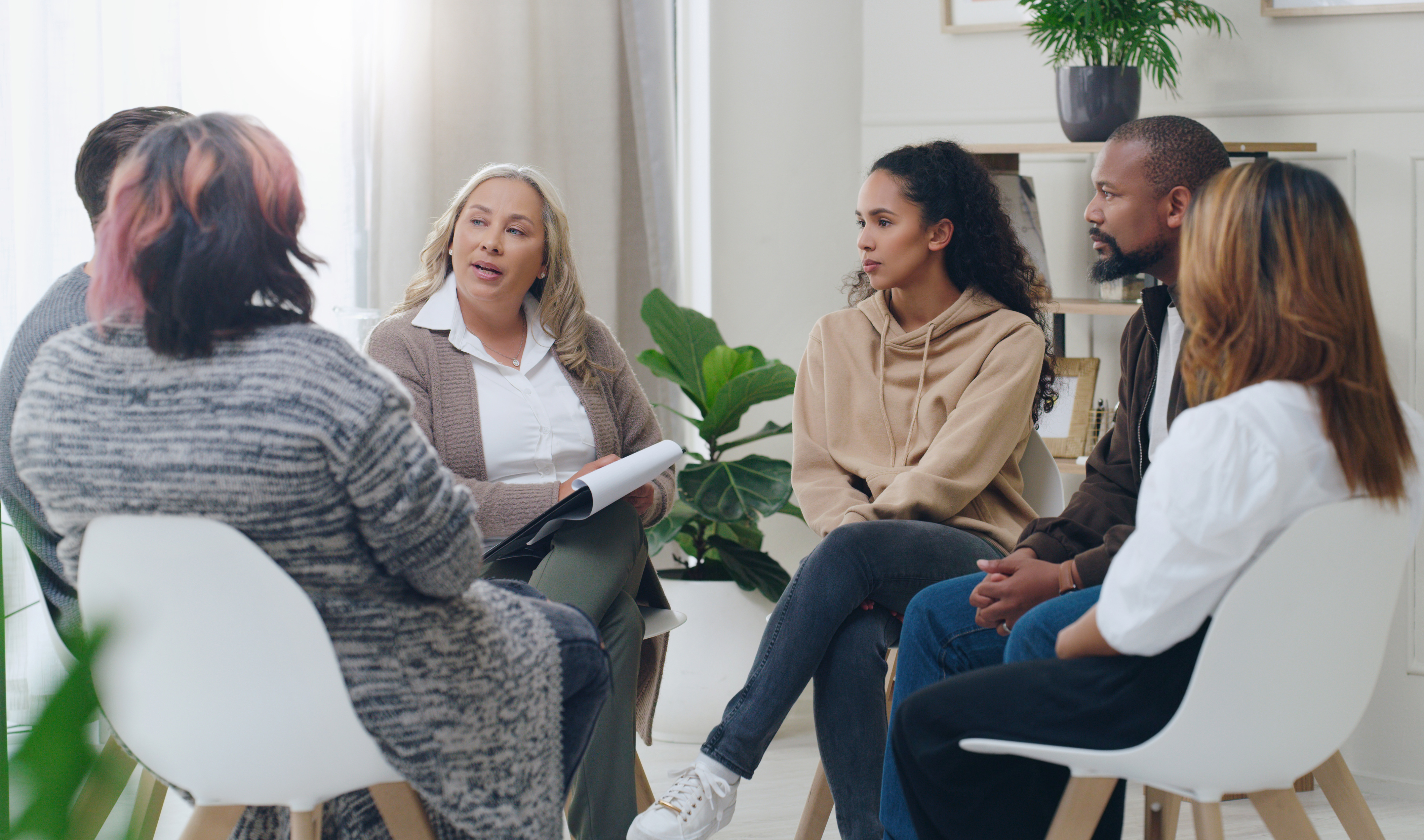 Social worker leading a group mental-health counseling session with diverse participants