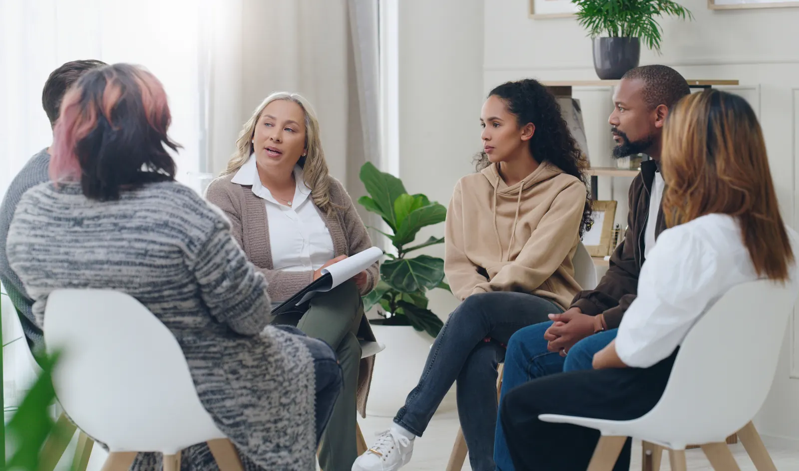 Social worker leading a group mental-health counseling session with diverse participants
